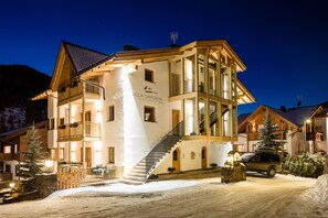 Ein mehrstöckiges Gebäude mit einer Treppe, die zum Eingang führt, umgeben von Schnee.