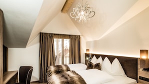 A hotel room with a large bed, a desk, a chair, and a chandelier.