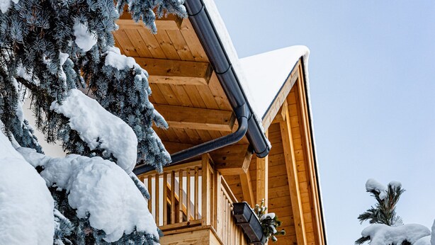 A multi-story wooden building with balconies and snow-covered trees.