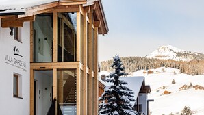 A wooden building with a sign reading "Villa Gardena" and a view of a snow-covered mountain.