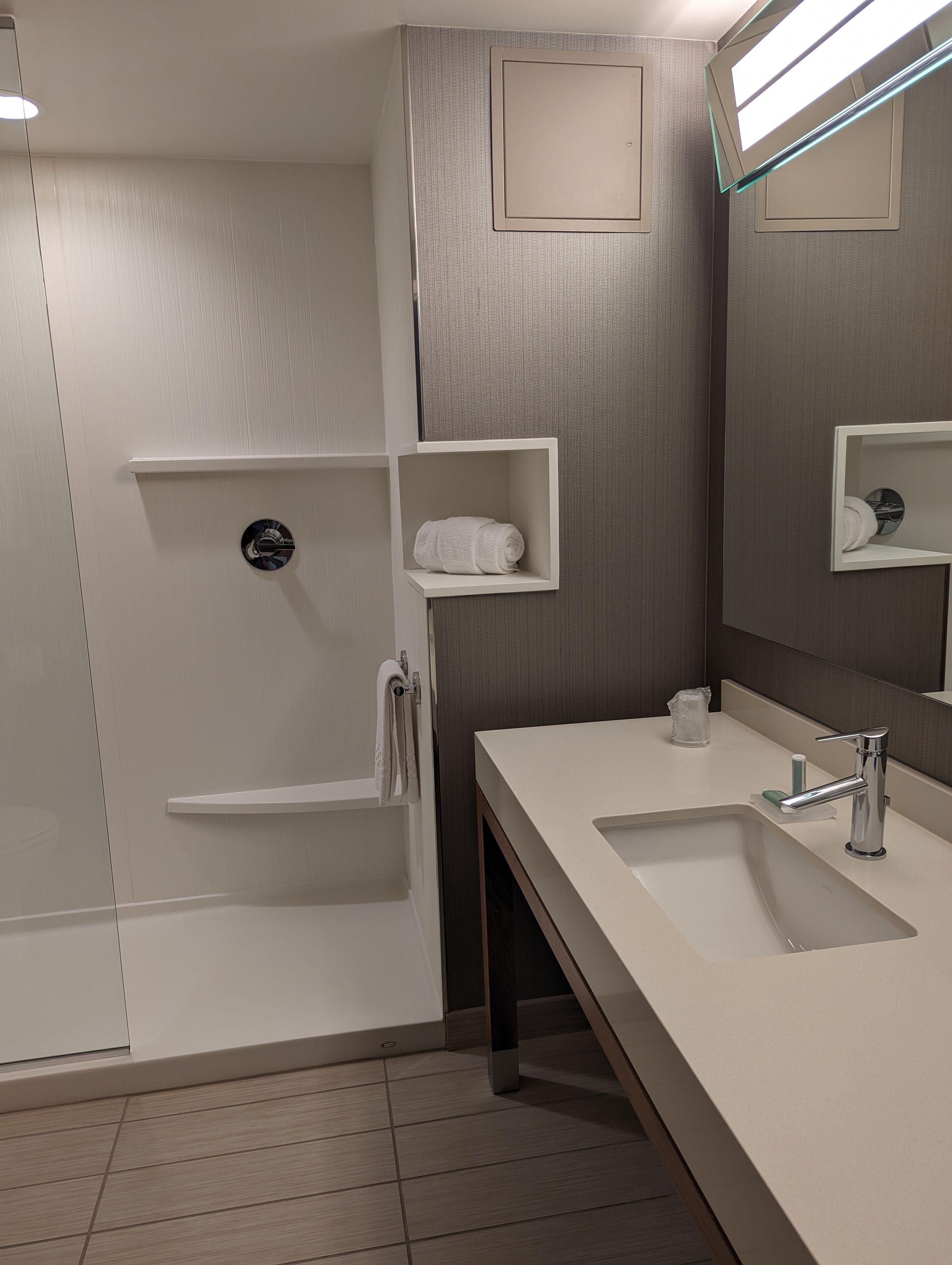 Un baño moderno con un lavamanos blanco, espejo y toallero.