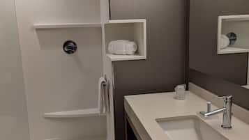 Un baño moderno con un lavamanos blanco, espejo y toallero.