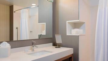 A modern bathroom with a large mirror, a sink, and a towel rack.