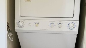 Una lavadora secadora compacta, blanca y de dos puertas, con perillas de control y un pequeño panel de visualización.
