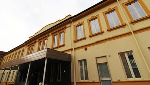Un immeuble à plusieurs étages, doté d’une façade beige, de nombreuses fenêtres à encadrements blancs et d’un espace d’entrée abrité.