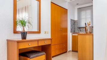 Une salle de bain moderne avec un meuble-lavabo en bois, un banc, une plante en pot et un miroir.