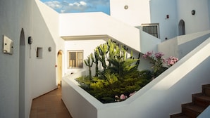 A white building with a staircase and a garden with cacti and flowers. - Elounda Alikes Suites & Studios (Agios Nikolaos)