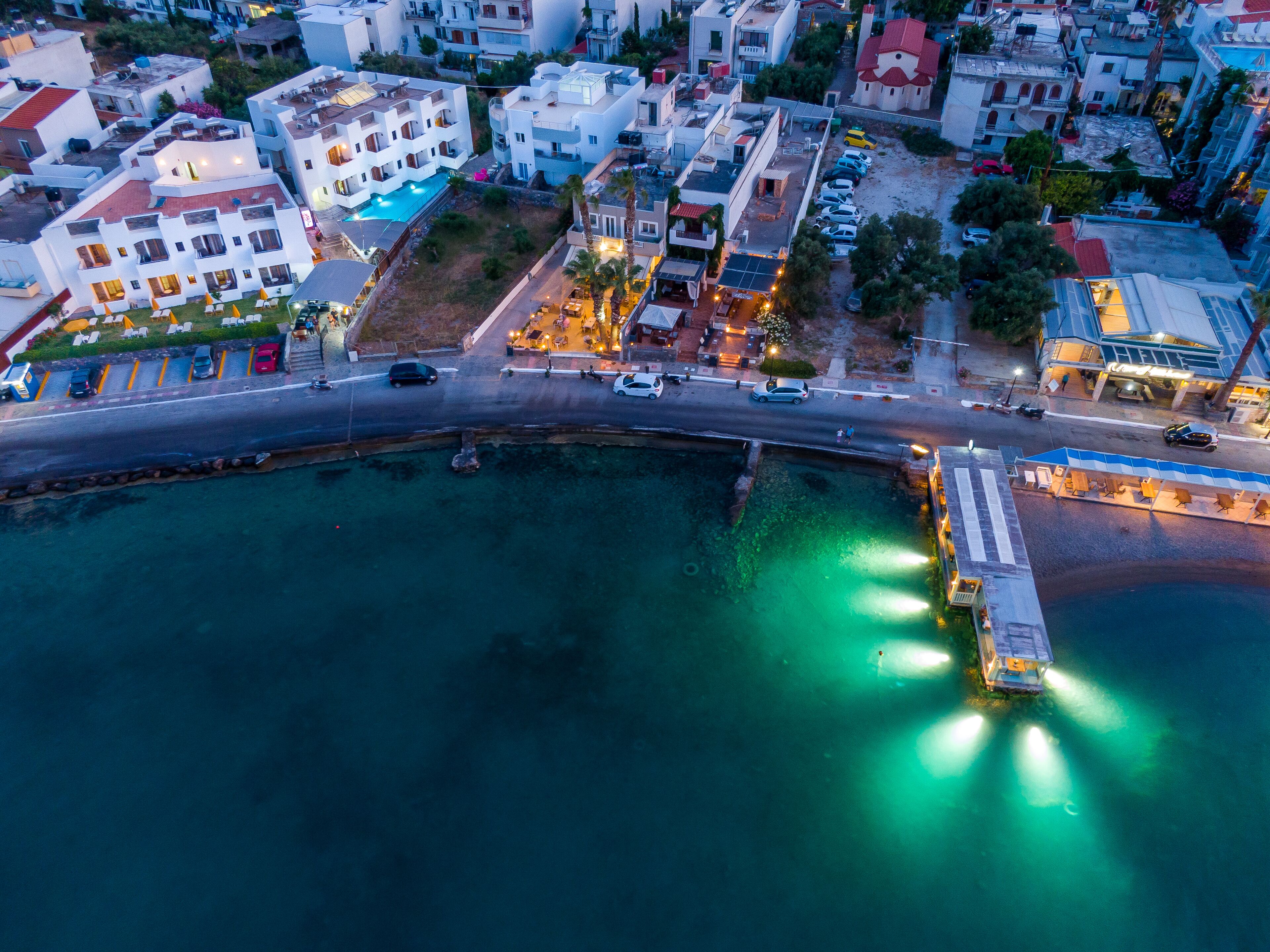 An aerial view of a coastal town with a marina, buildings, and a road.