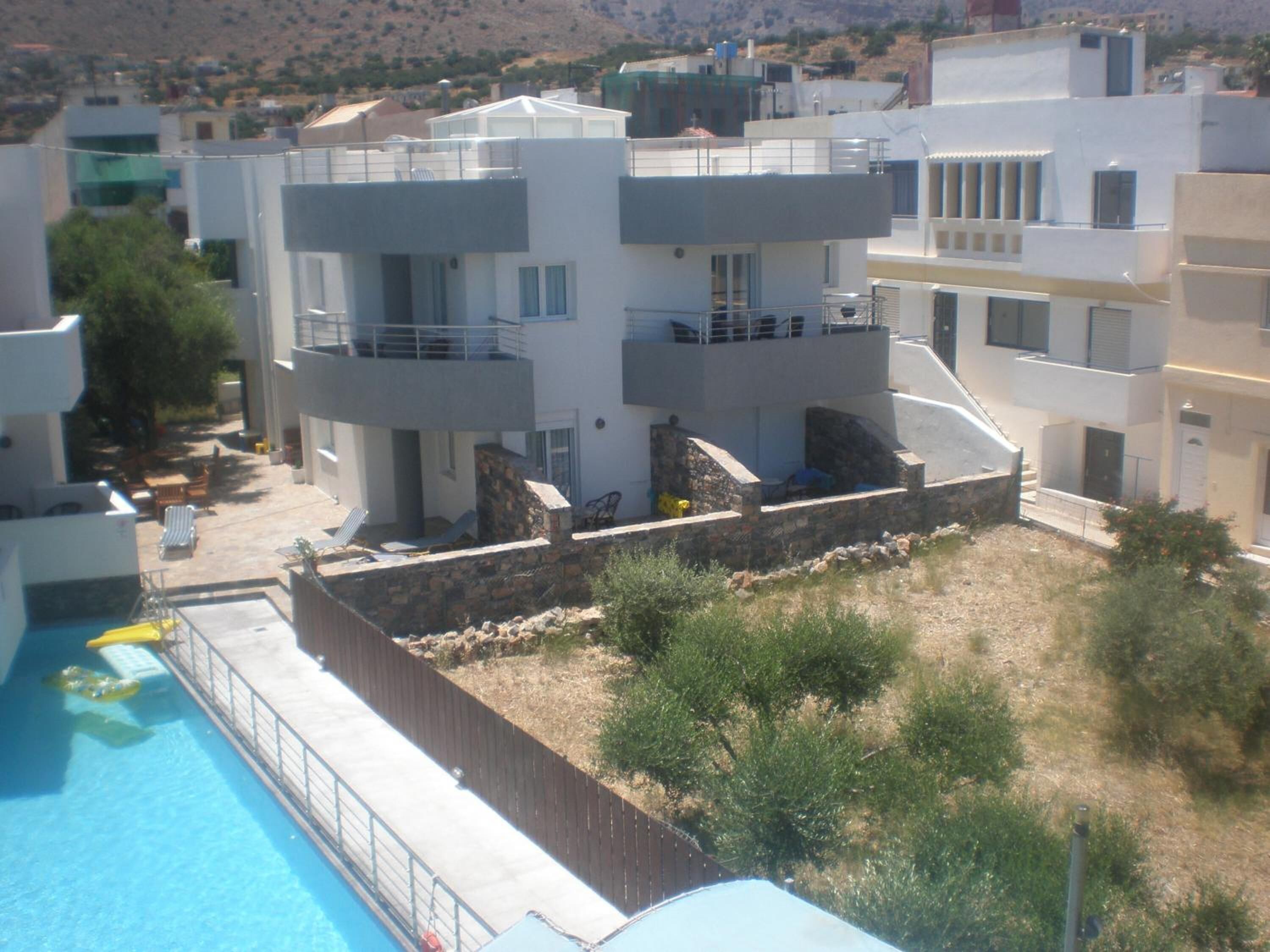 Un edificio moderno de varios pisos con balcones, piscina y un muro de contención de piedra.