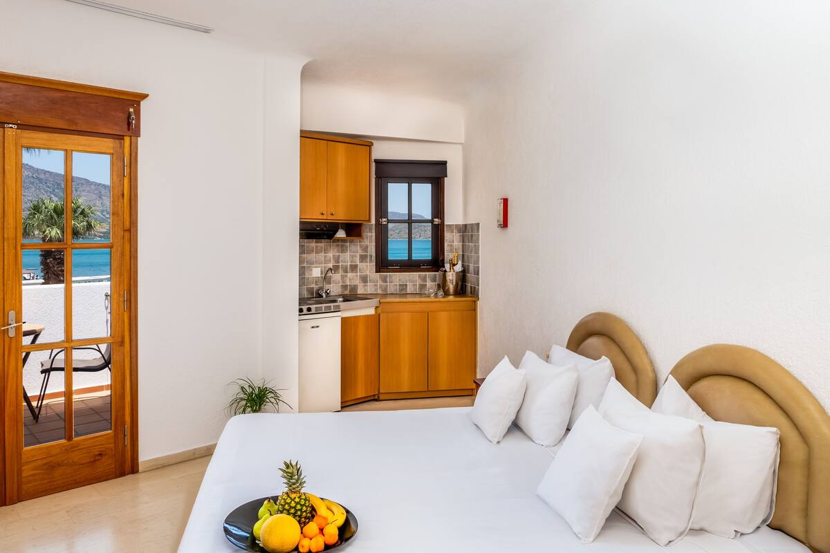 A bedroom with a bed, white pillows, and a fruit bowl on the bedside table.