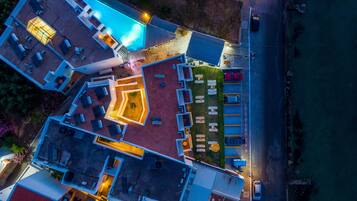 Vista aérea de un hotel con piscina, mobiliario exterior y aparcamiento.