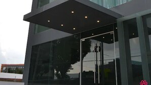 A modern building with a glass entrance and a flat roof. - Hotel y Tú (Guadalajara)