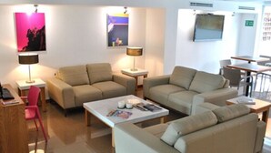 A modern living room with beige sofas, a coffee table, and two side tables with lamps. - Hotel y Tú (Guadalajara)