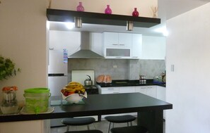 A modern kitchen with white cabinets, a black countertop, and a stainless steel range hood.