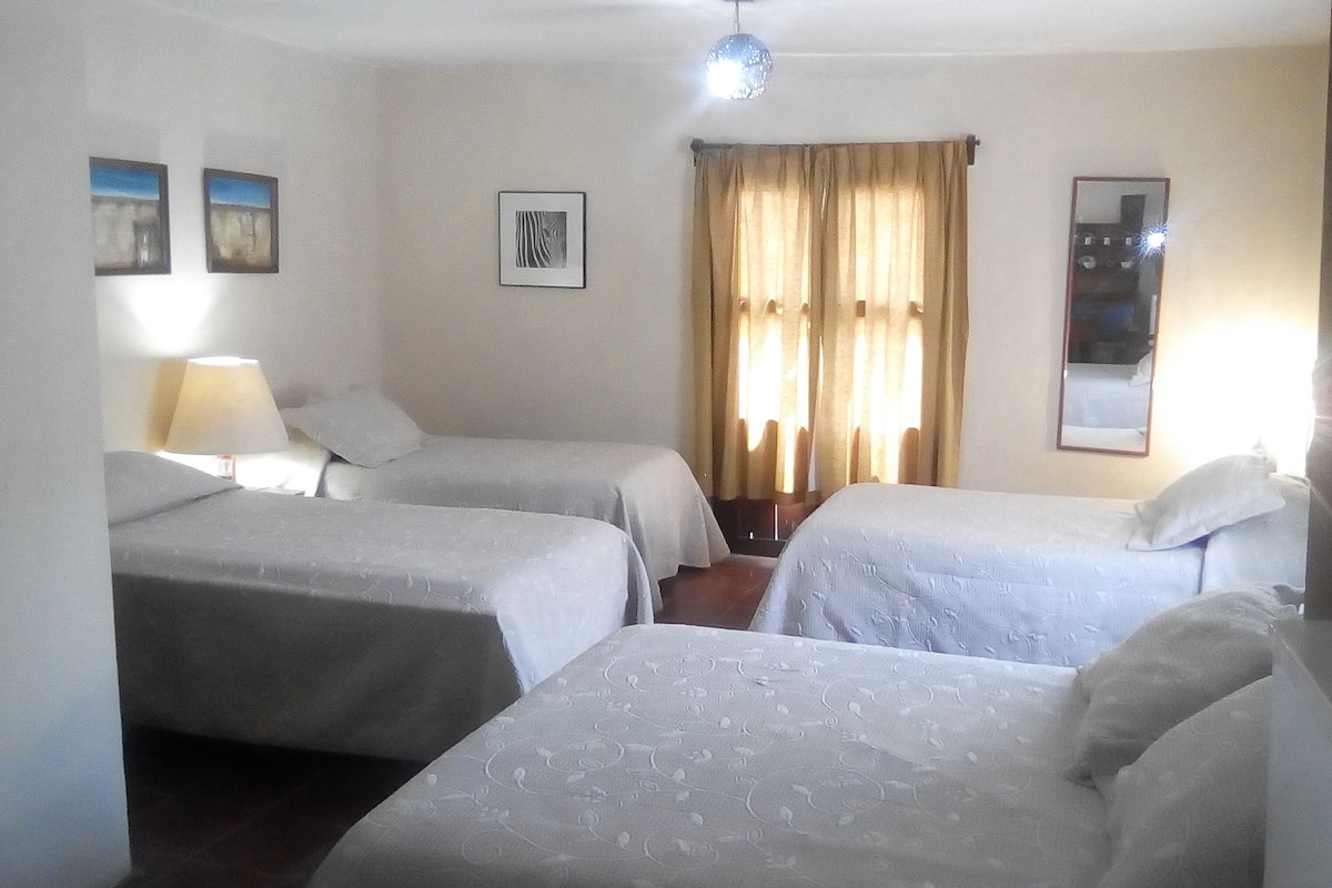 Una habitación de hotel con dos camas, una ventana con cortinas, una lámpara y un espejo.