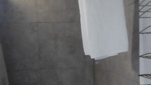 Een kleine, afgesloten douchehoek met een betegelde wand en een wit gordijn.