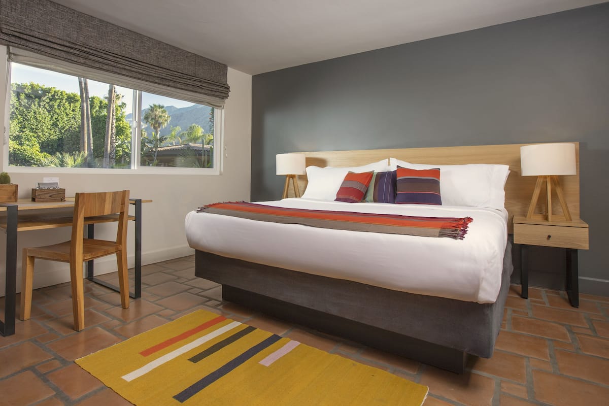 A bedroom with a bed, bedside tables, a desk, and a chair.