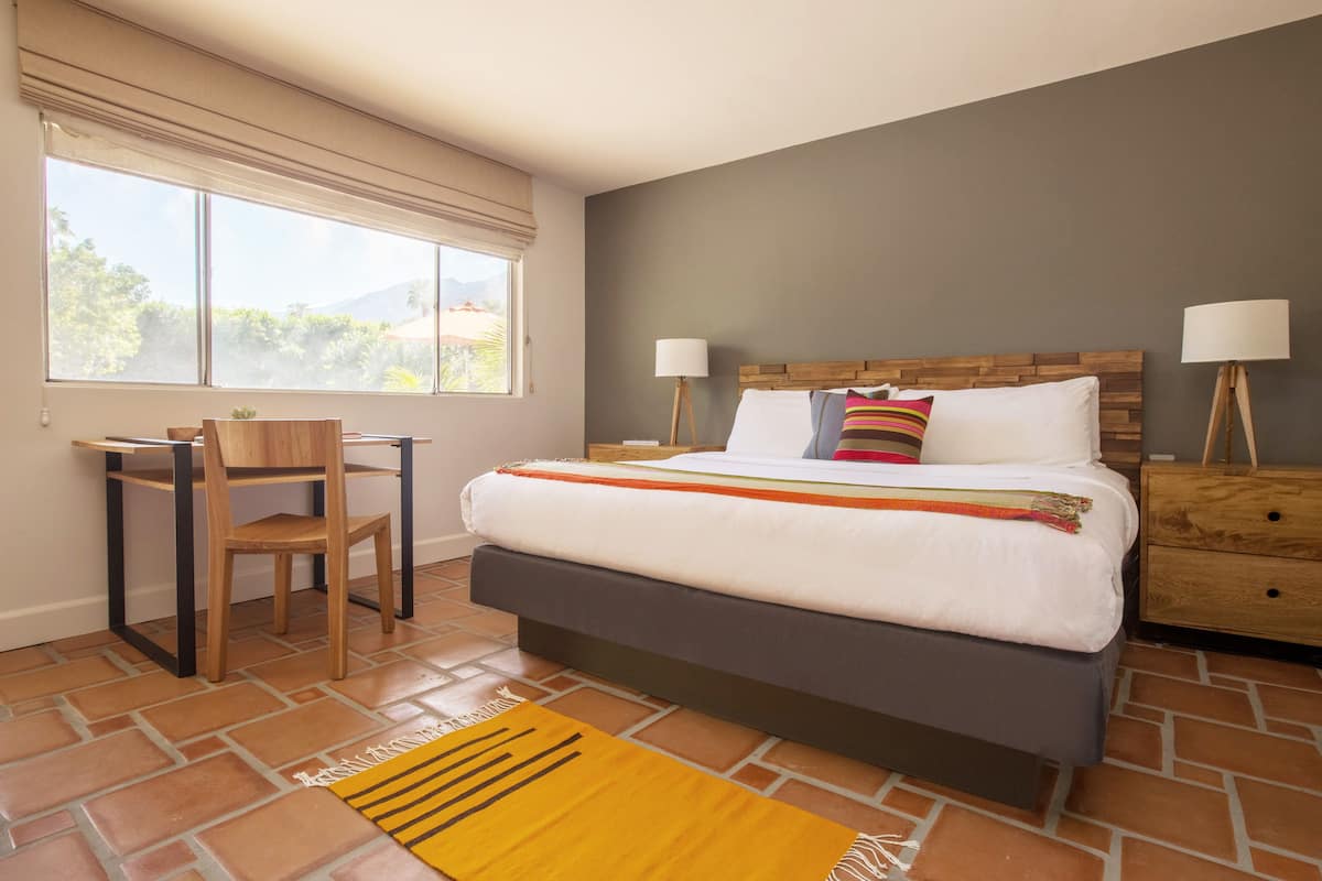 A bedroom with a bed, bedside tables, a desk, and a chair.
