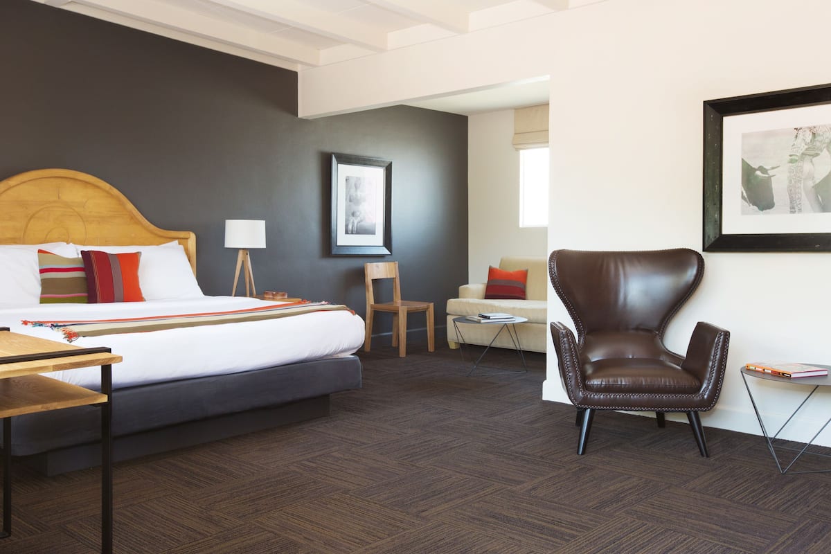 A hotel room with a bed, a desk, a chair, and a small table.