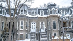 Una casa señorial histórica con entrada central, varias ventanas y una escalera que conduce a la puerta principal.