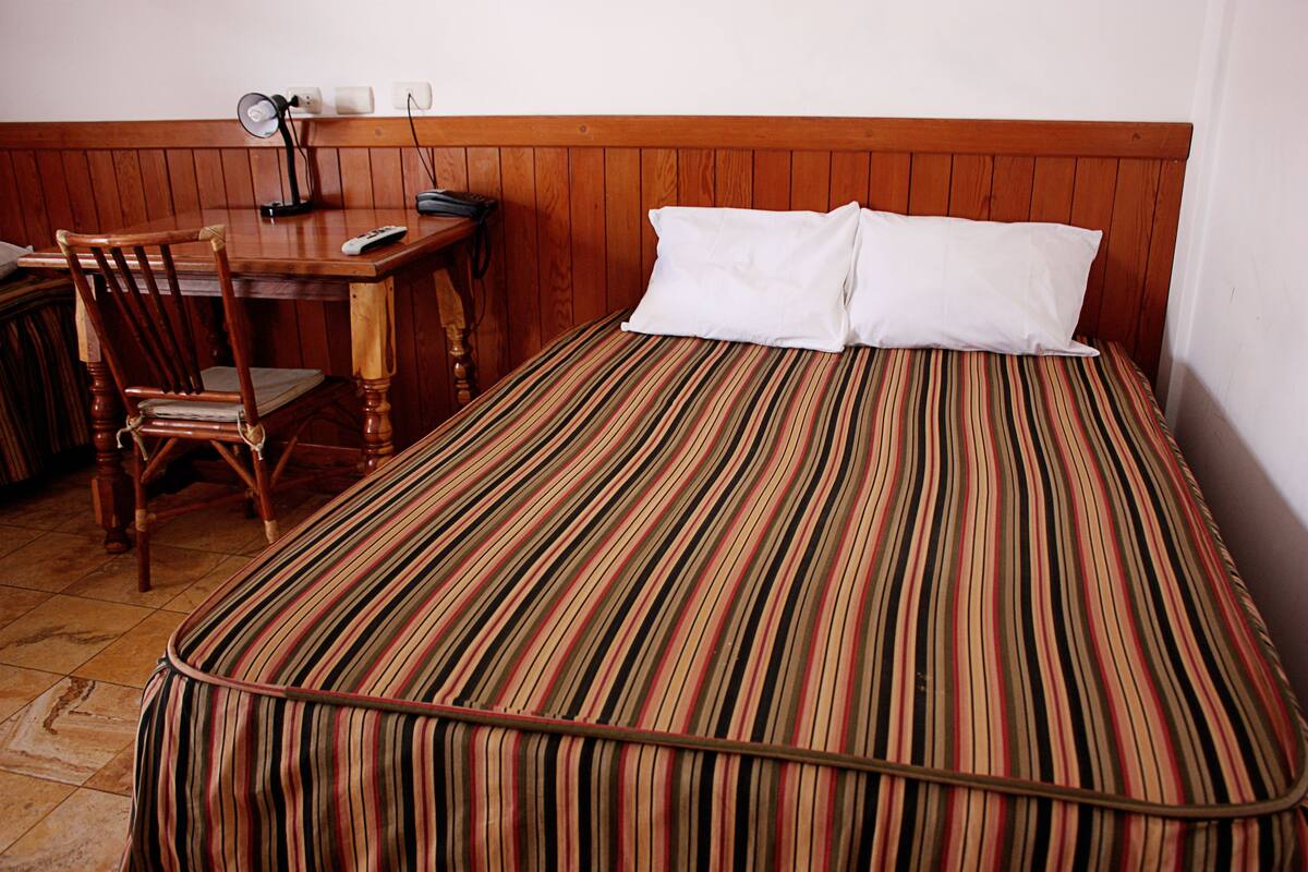 A room with a bed, a wooden desk, and a chair.