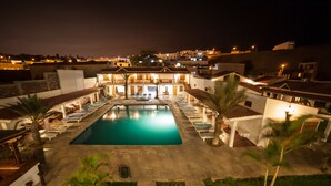 A pool area with lounge chairs and a swimming pool, surrounded by buildings with balconies and outdoor seating. - El Huarango Hotel (Ica)
