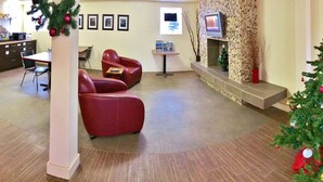 A hotel lobby with a Christmas tree, seating area, and a reception desk. - Grande Mountain Lodge (Grande Cache)