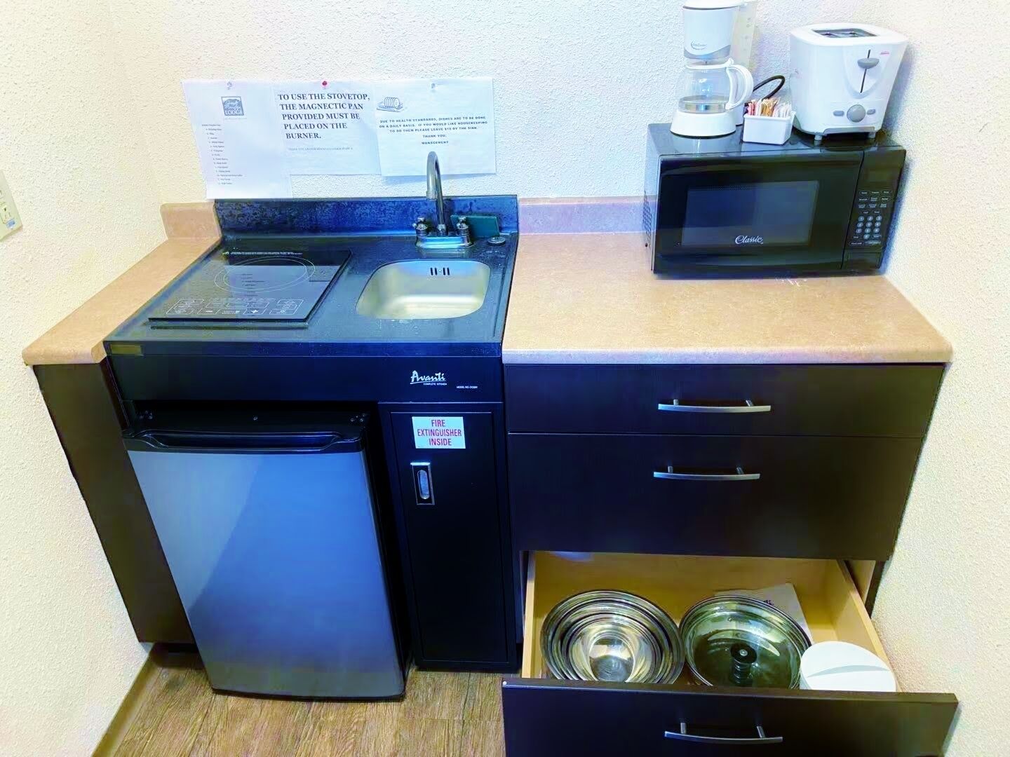 Een kleine keuken met een vaatwasser, een magnetron en een koffiezetapparaat.