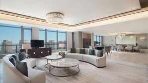 A spacious living room with a large sofa, a coffee table, and a TV. There is a dining area with chairs and a chandelier. - Sheraton Chuzhou Hotel (Chuzhou)