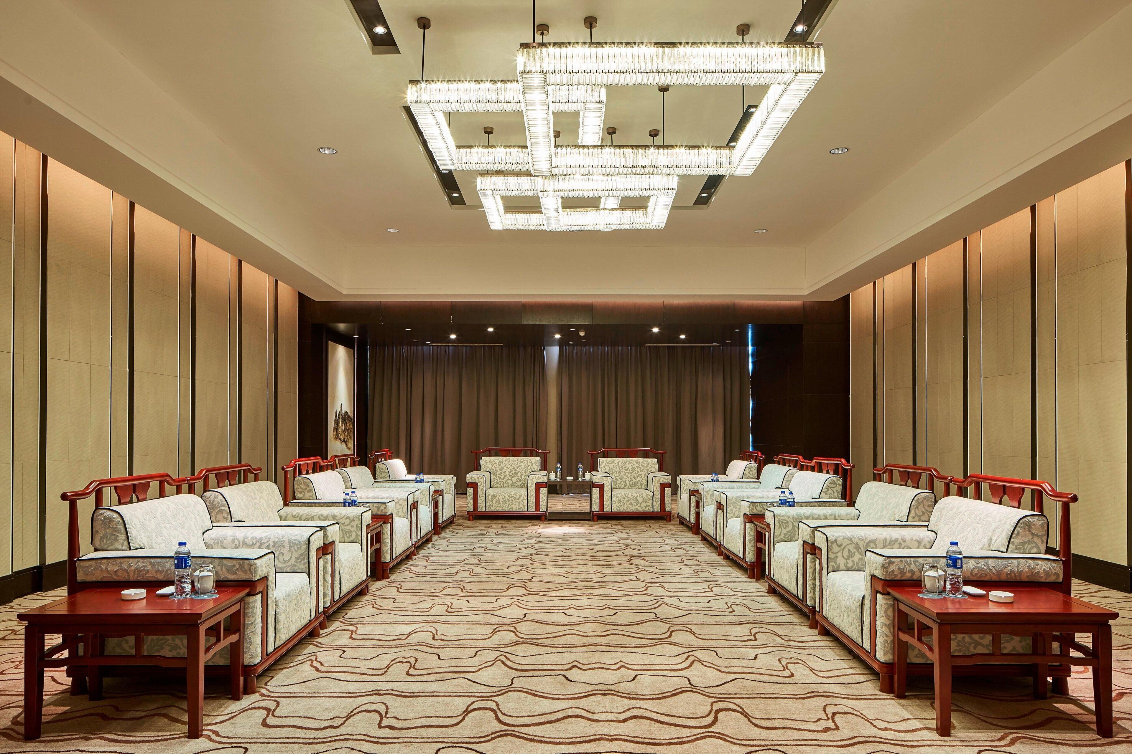 A conference room with a large chandelier, multiple sofas, and tables arranged for meetings.