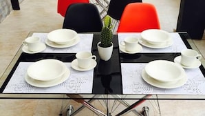 A dining area with tables set for four, each with white plates, cups, and a small potted plant. - Hotel Metro 26 (Bogotá)