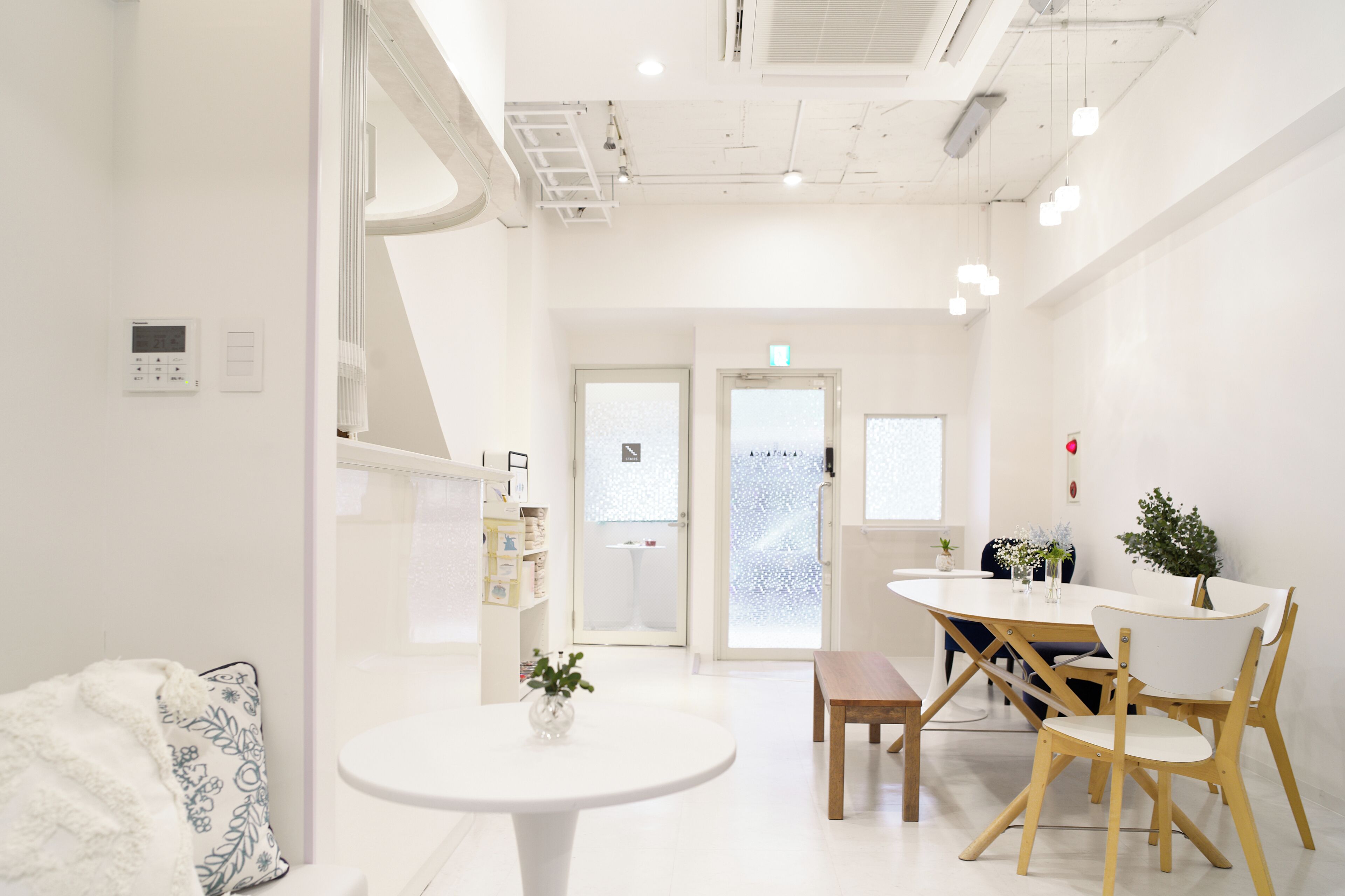 A bright, modern room with a round table, chairs, and a bed with a patterned blanket.