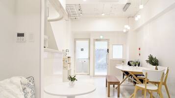 A bright, modern room with a round table, chairs, and a bed with a patterned blanket.