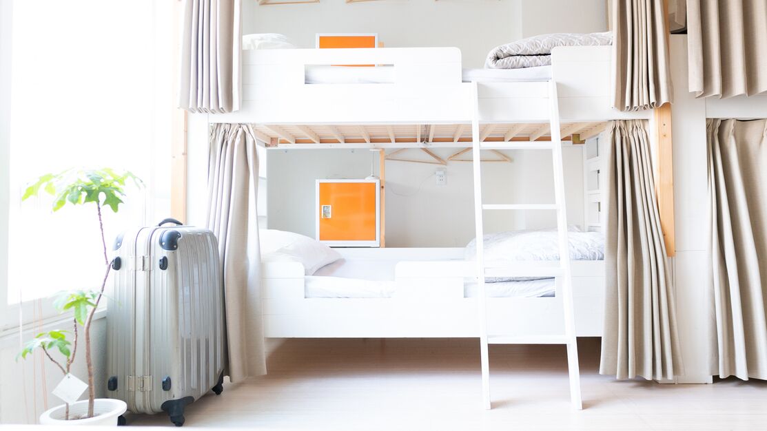 A bunk bed room with a suitcase, a radiator, and curtains.
