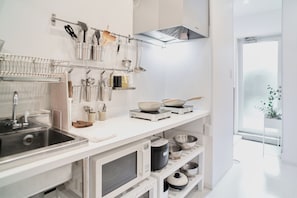 A modern kitchen with a white countertop, stainless steel appliances, and utensils hanging on a rack.