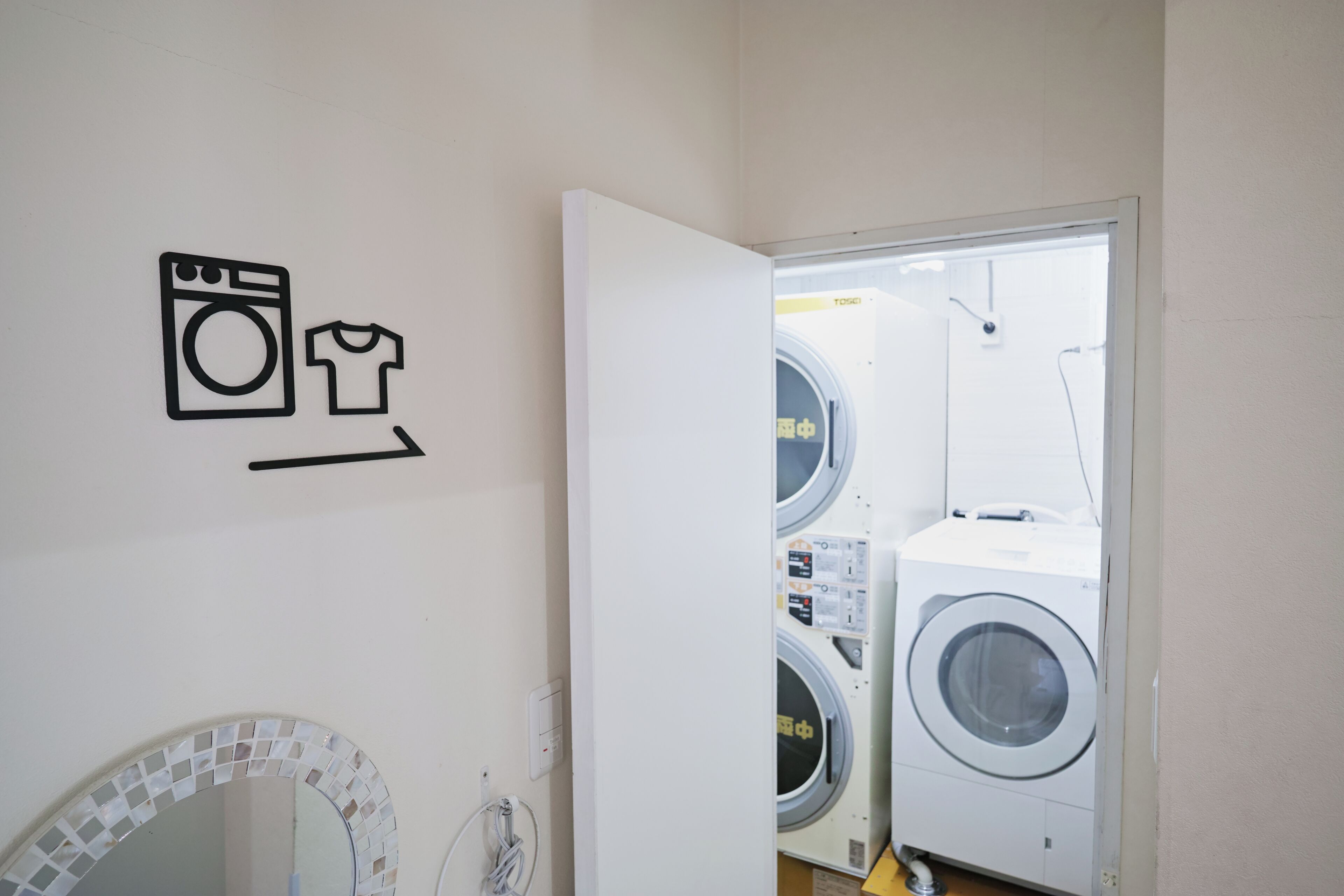 A laundry room with a washing machine, dryer, and a wall-mounted sign indicating the location.