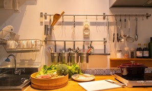 Une cuisine avec une planche à découper en bois, un évier et divers ustensiles accrochés au mur.
