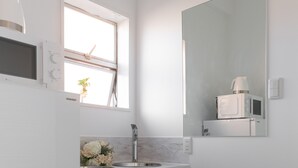 Een moderne badkamer met een grote spiegel, een wastafel en een raam.