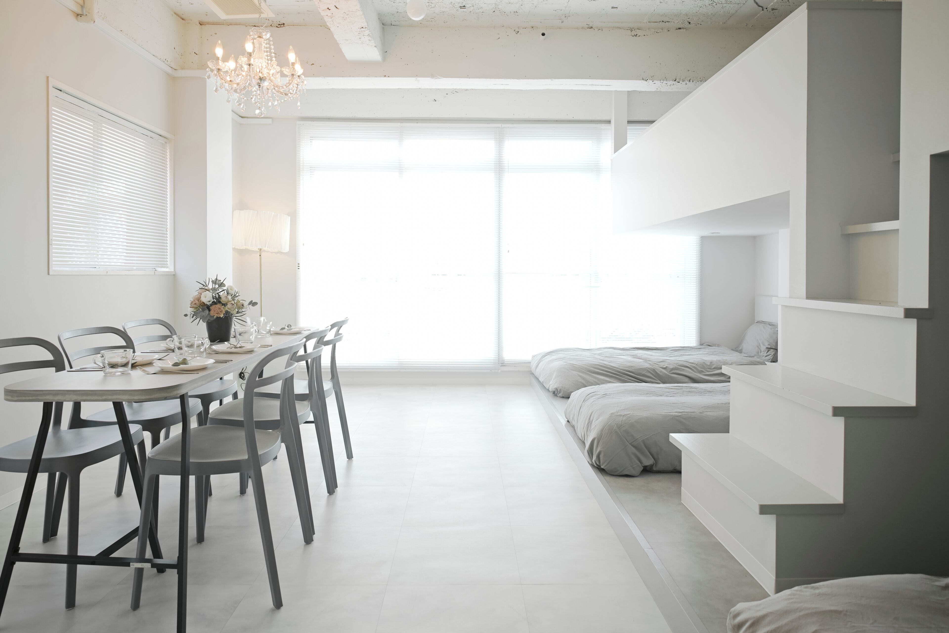 Quarto moderno e minimalista com área de refeições, cama e escada.