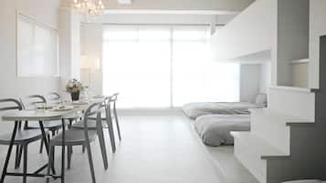 Quarto moderno e minimalista com área de refeições, cama e escada.