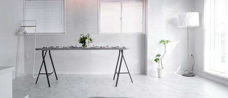 A minimalist room with a bed, a table with a vase of flowers, and a floor lamp.