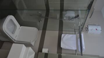 Un bany modern amb plat de dutxa de vidre, vàter, rentapla i barra de tovalloles.