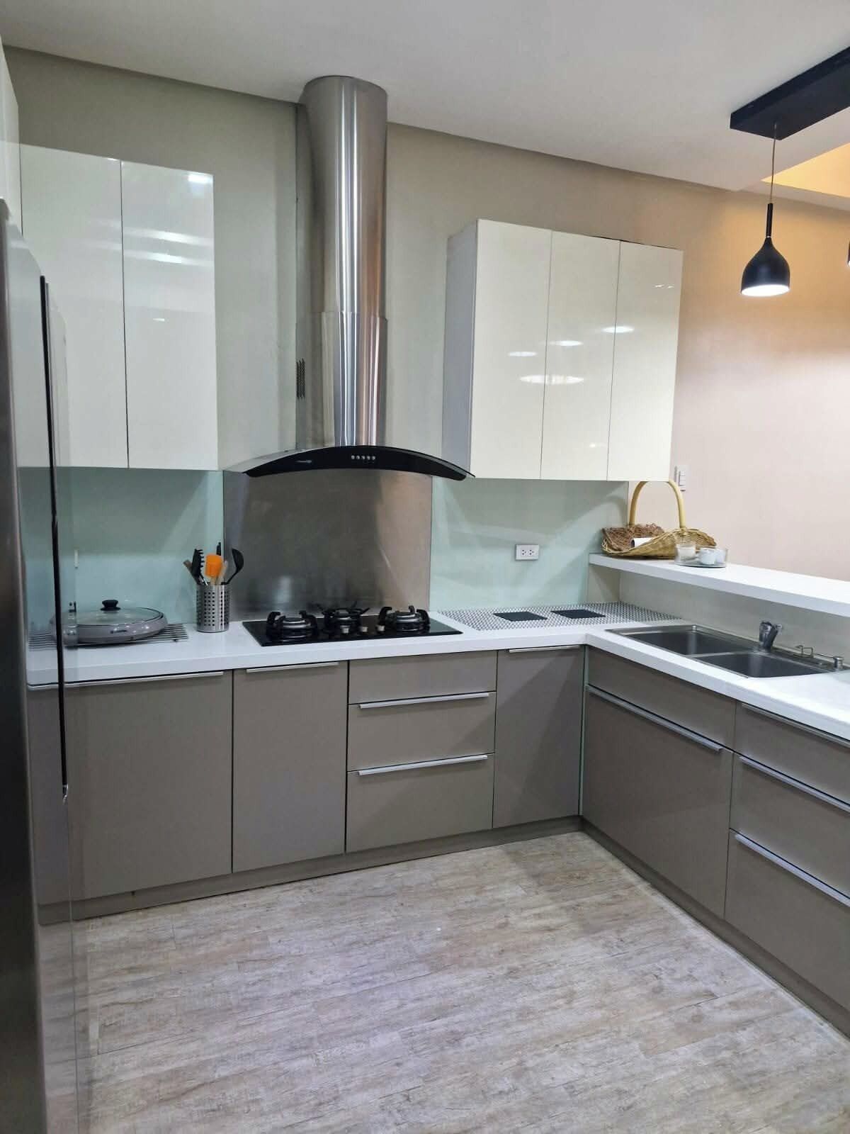 Una cocina moderna con electrodomésticos de acero inoxidable, armarios blancos y un ventanal grande.
