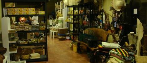 Una tienda estrecha y abarrotada, con estantes llenos de diversos artículos, incluyendo textiles y productos para el hogar.
