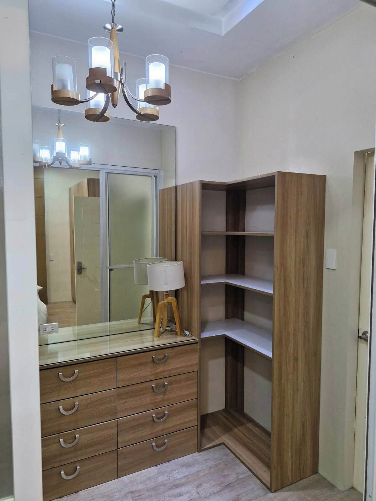 A modern bathroom with a wooden vanity, a mirror, and a chandelier.