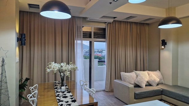 A modern living room with a sofa, a dining table with chairs, and pendant lighting. - F2M Tower (Legazpi)