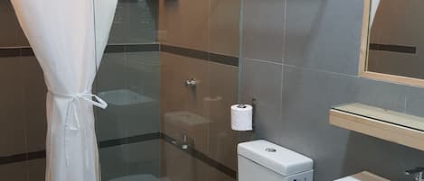 Une salle de bain moderne avec une douche à parois de verre, des toilettes et un lavabo.