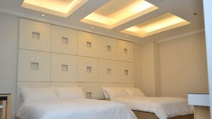 A modern bedroom with two beds, a built-in wardrobe, and recessed ceiling lighting. - F2M Tower (Legazpi)