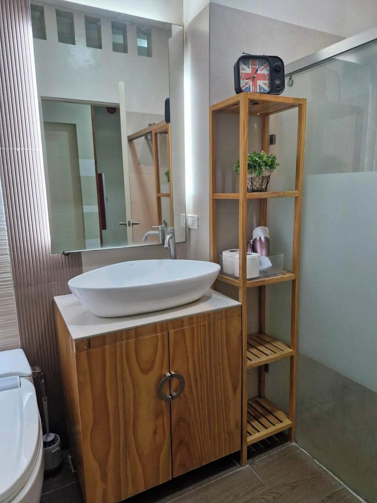 Een moderne badkamer met een houten wastafelmeubel, een witte wasbak en een spiegel.