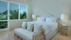 A bedroom with a bed, two bedside tables, a sofa, and large windows. - Room & Vespa 4 (Seminyak)